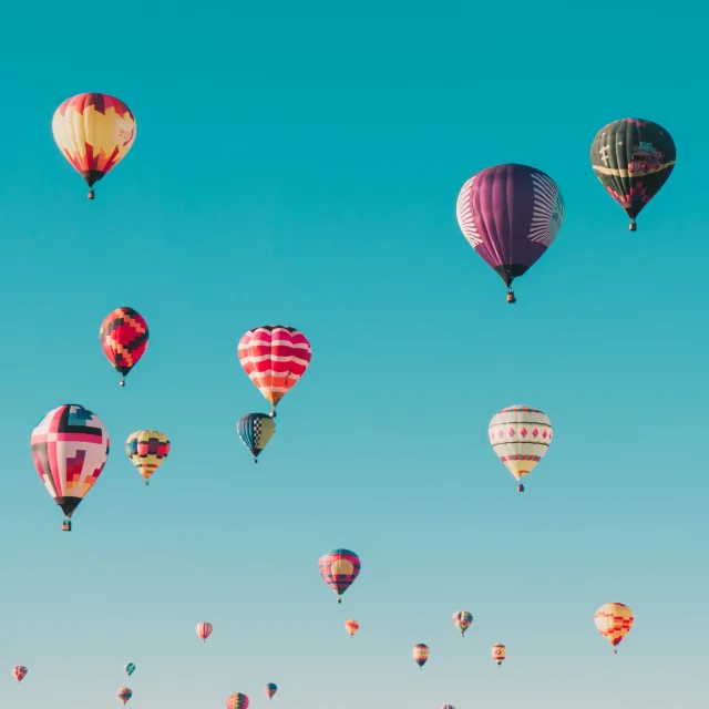 Colourful hot air balloons rising into a blue sky