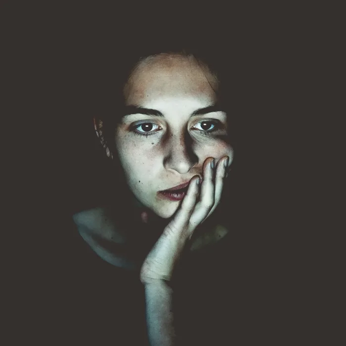 Portrait en clair-obscur d'une personne, visage inquiet, main portée à la bouche