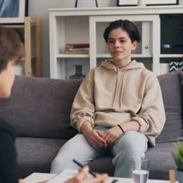 Teenager seated in session, facing a practitioner taking notes