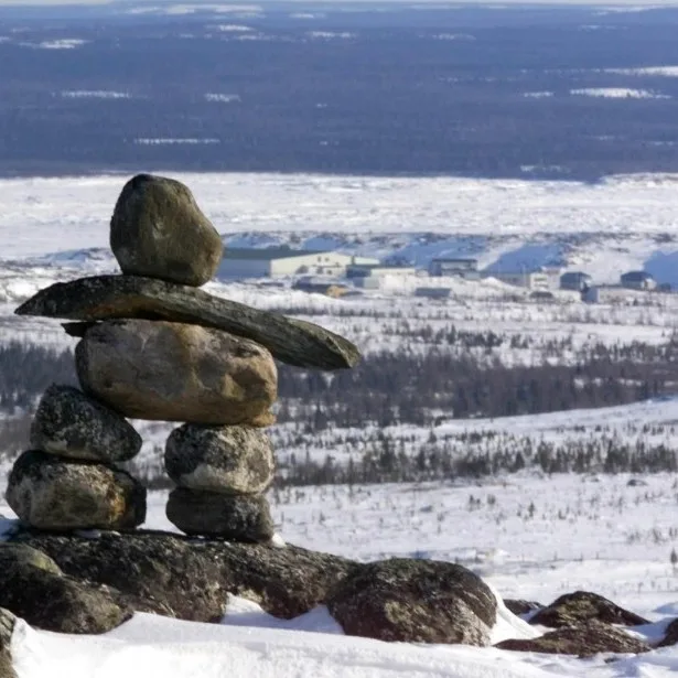 Un inukshuk sur la neige, au-dessus d'un village du Nord-du-Québec